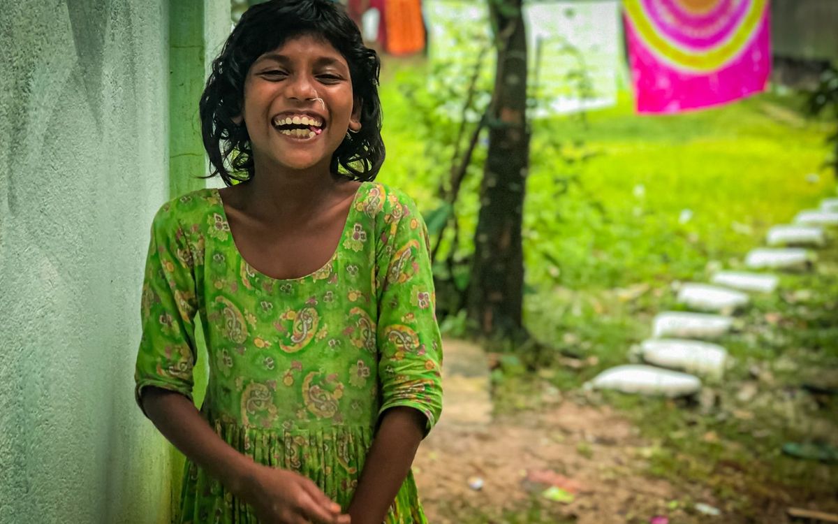 A young girl laughing in the garden of her home